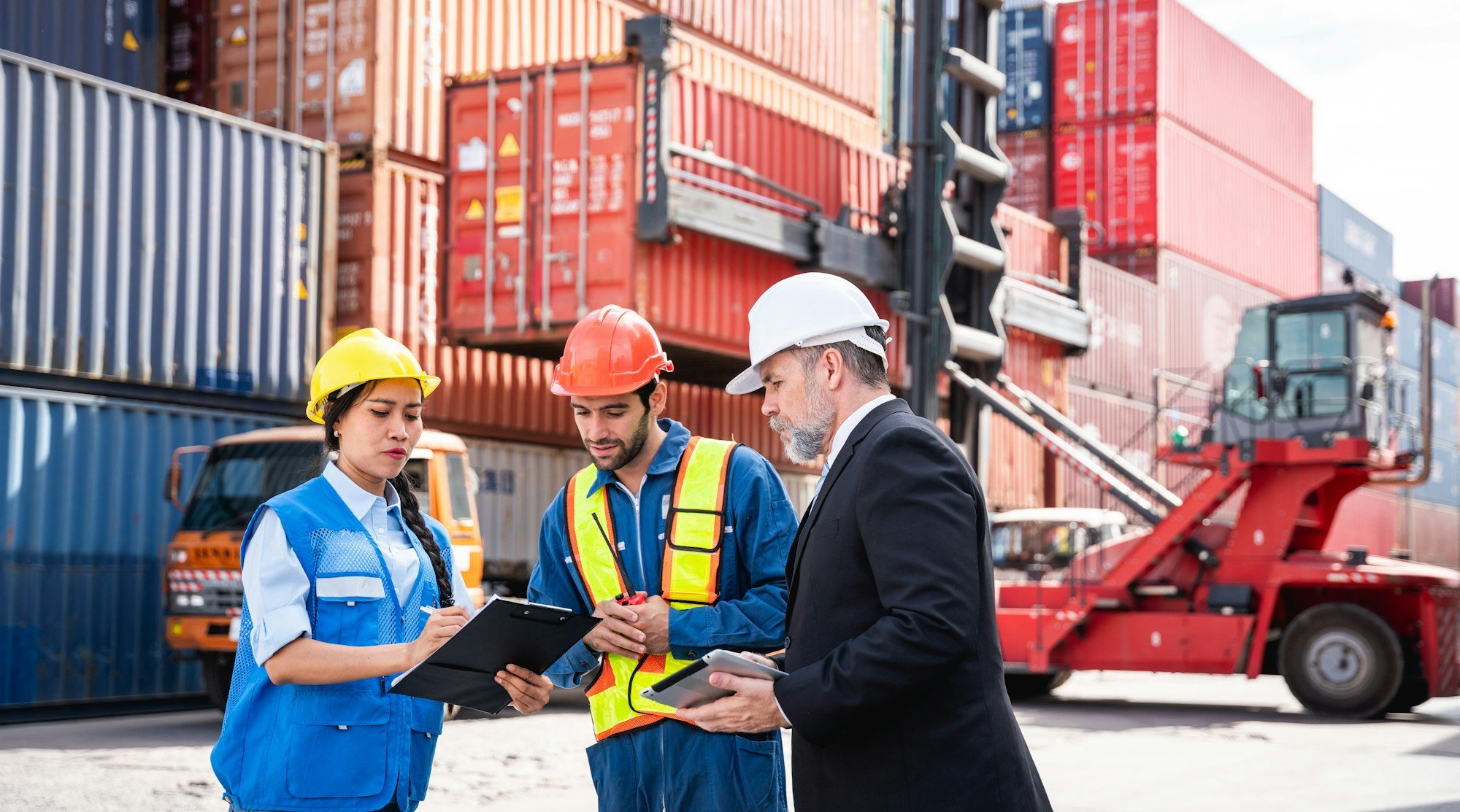 Businessman, Engineer or foreman talking and checking inventory or task details at container yard.